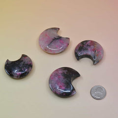 Set of four half-moon shaped objects with a colorful pattern on a beige background.