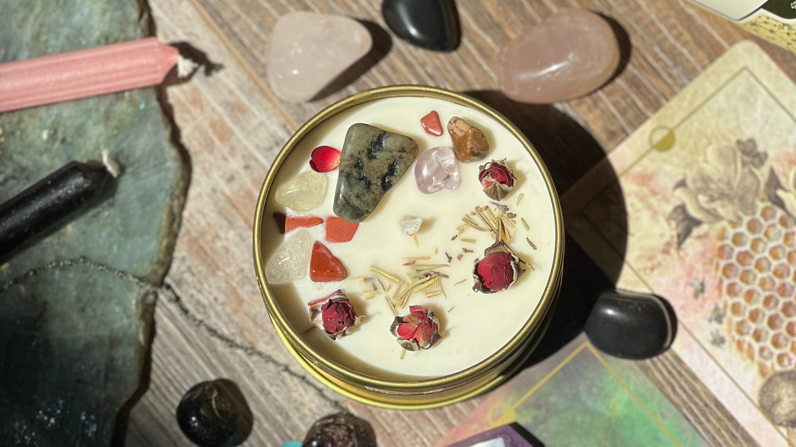 Top-down view of a small round container with decorative elements on a textured surface with crystals and a bottle.