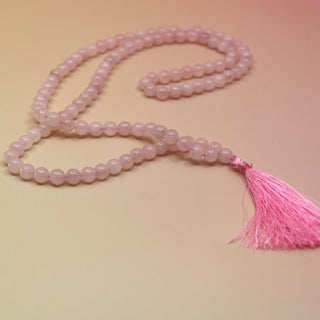 Rose Quartz 108 Mala Necklace on pink and orange background