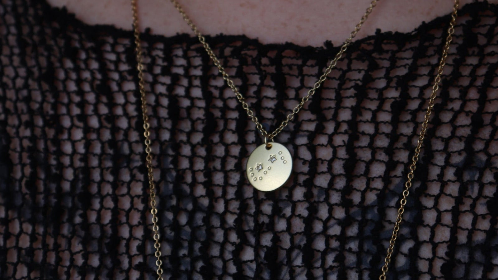 Someone wearing the Scorpio 14k Gold Dipped Nickel-Free Zodiac Necklace with a black net top.