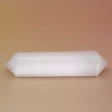 Selenite Crystal Wand on an orange and pink background 