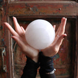 Hands holding a large crystal ball in front of an ornate, colorful background