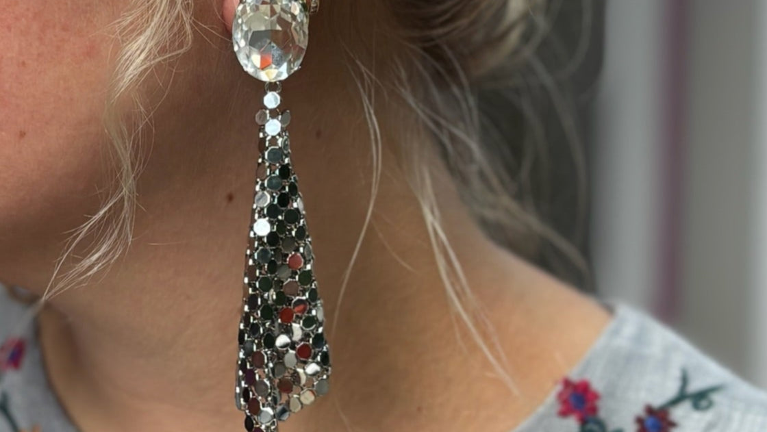 Close-up of a woman wearing a decorative disco earrings with a blurred background