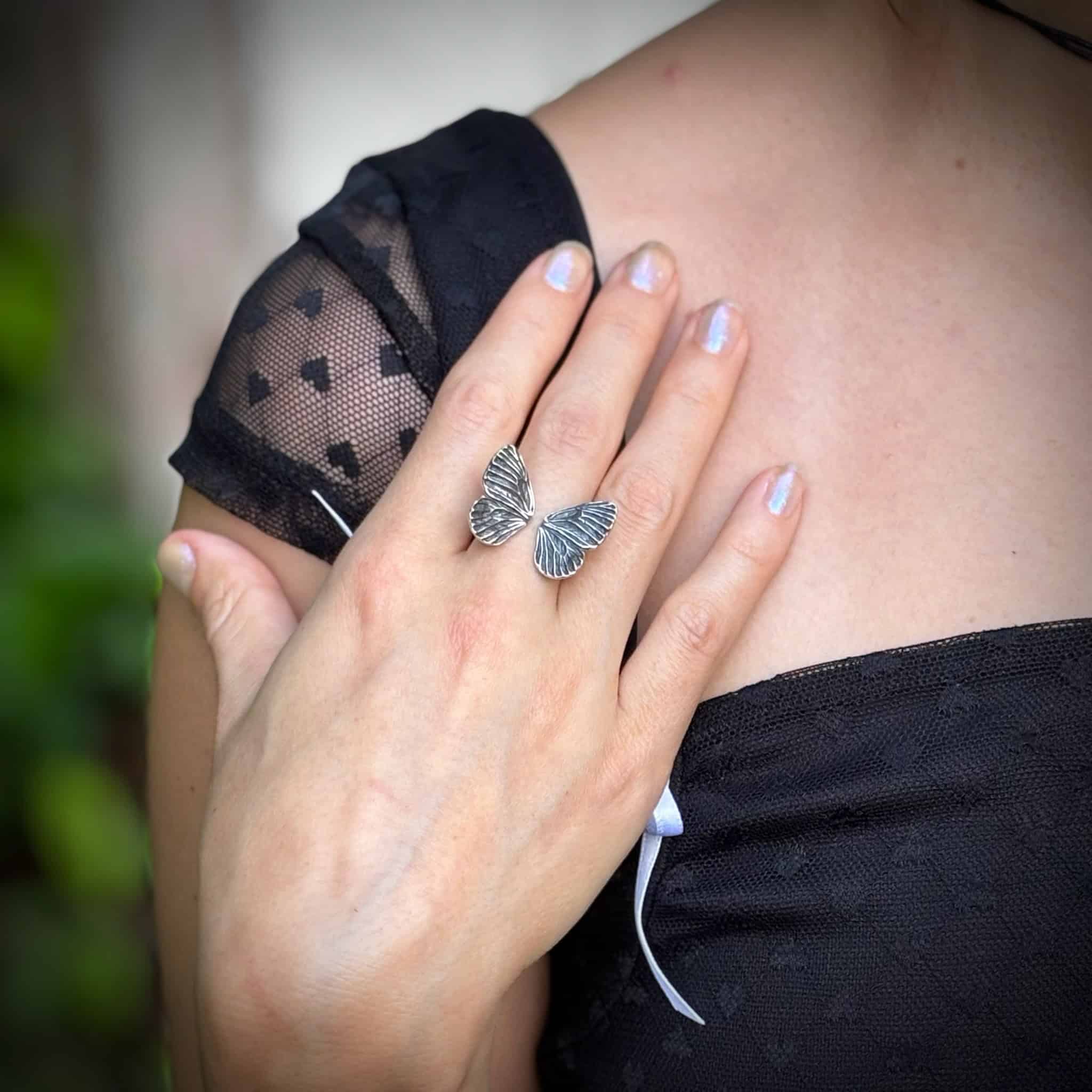 Person wearing a butterfly ring on a blurred natural background