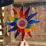 Colorful stained glass sunflower decoration held by a hand with a blurred background