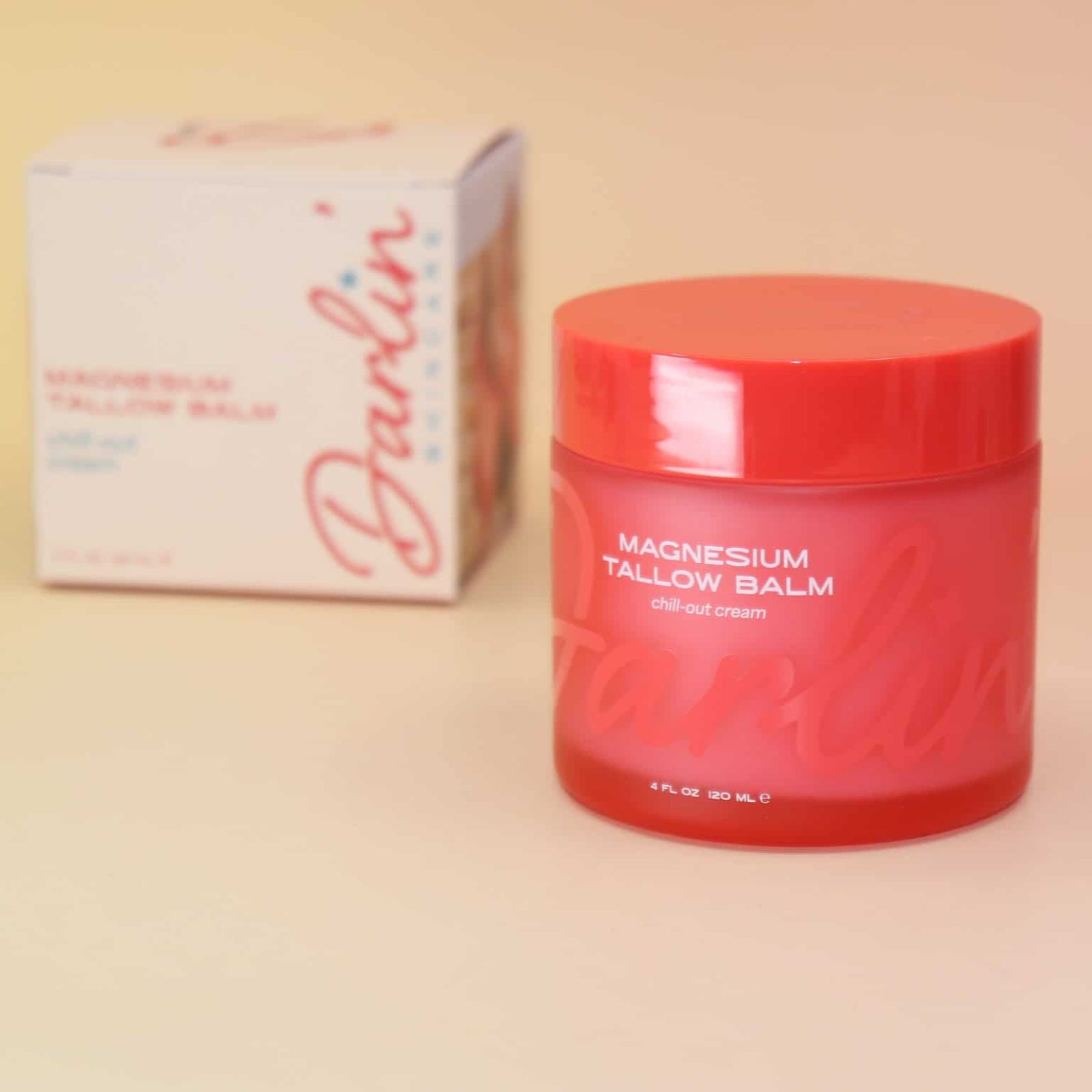 Red jar of balm with a box labeled 'Darlin' on a beige background
