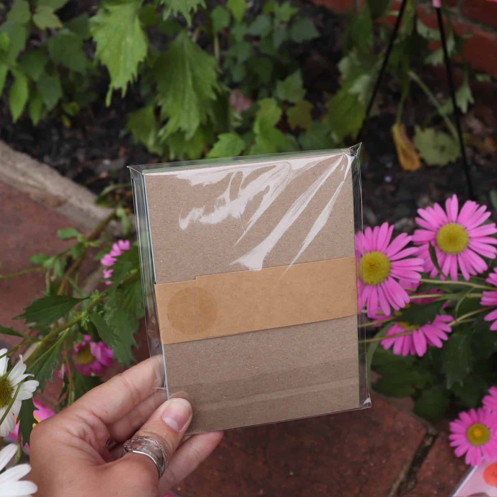 Hand holding a small rectangular mirror with floral background
