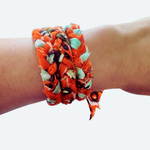 Wrist wearing two colorful fabric bracelets on a white background