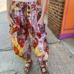 Model wearing red and purple tie-dye cargo pants with moon phase design with hands in pocket