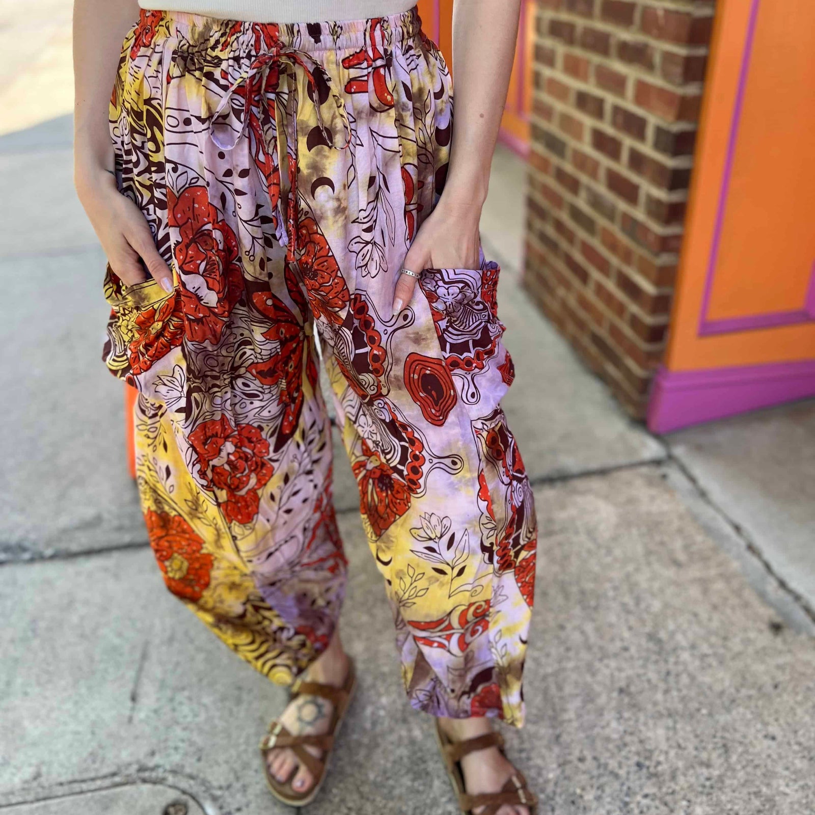 Model wearing red and purple tie-dye cargo pants with moon phase design with hands in pocket