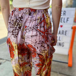 Model wearing red and purple tie-dye cargo pants with moon phase design close up view of back of pants