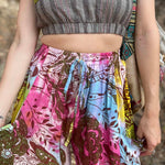 Rainbow tie-dye cargo pants with green floral moth pattern close up view showing midriff and crop top