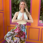 Rainbow tie-dye cargo pants with green floral moth pattern with model in yoga pose
