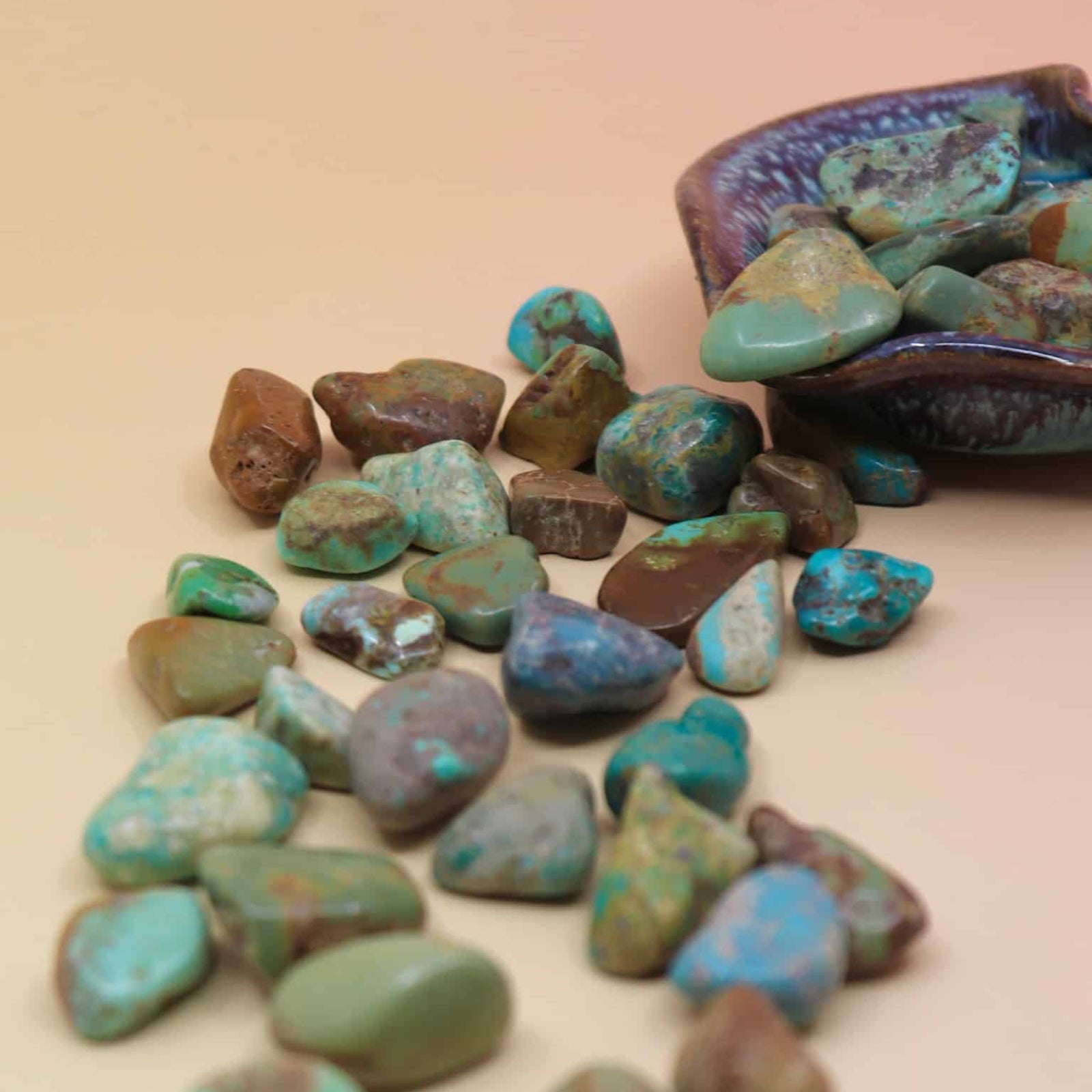 Turquoise stones with a decorative container on a beige background