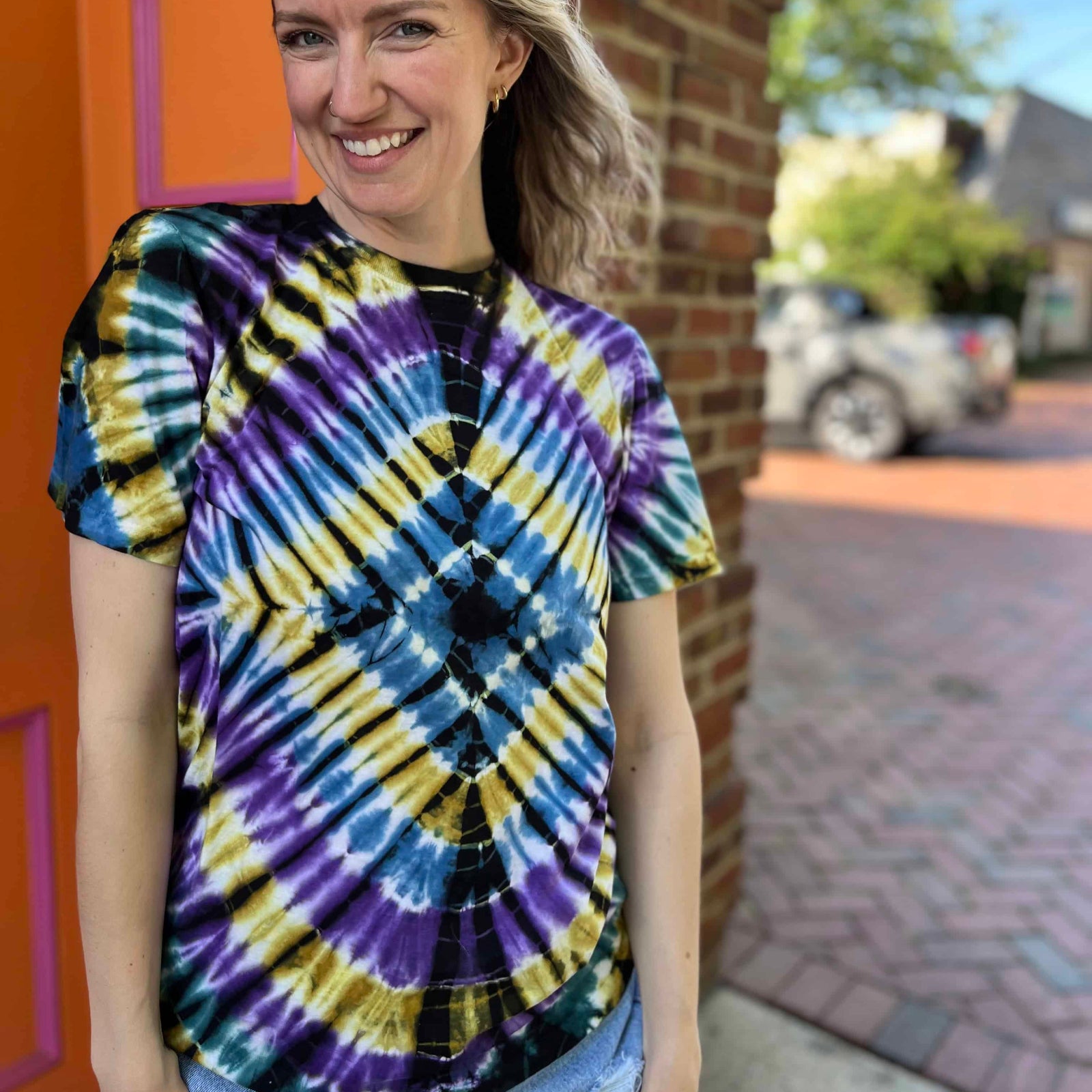 model smiling wearing black blue purple and yellow tie dye t shirt