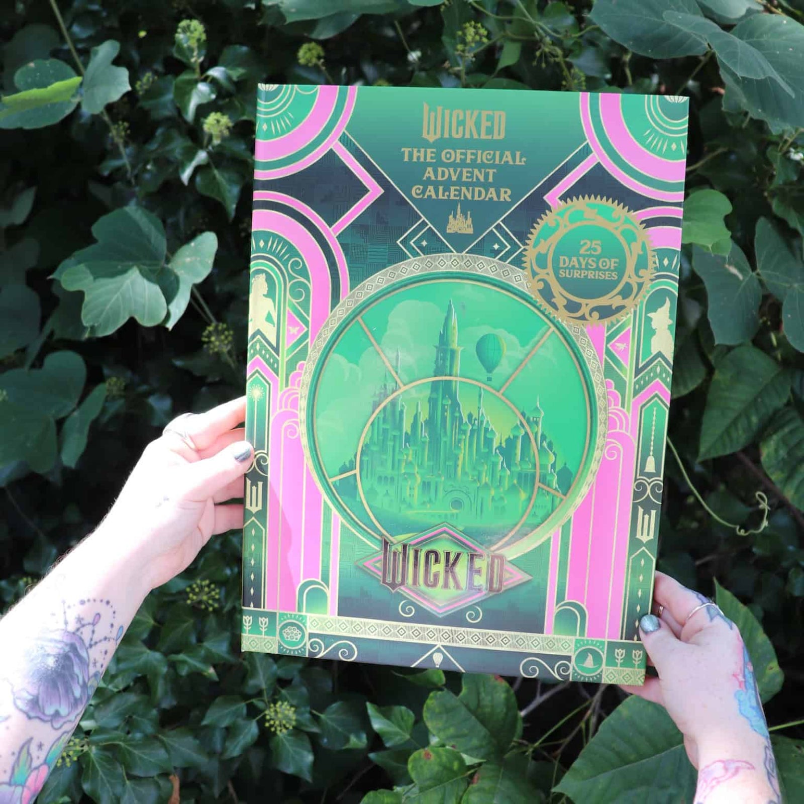 Green and pink book titled 'Wicked' held against a leafy green background