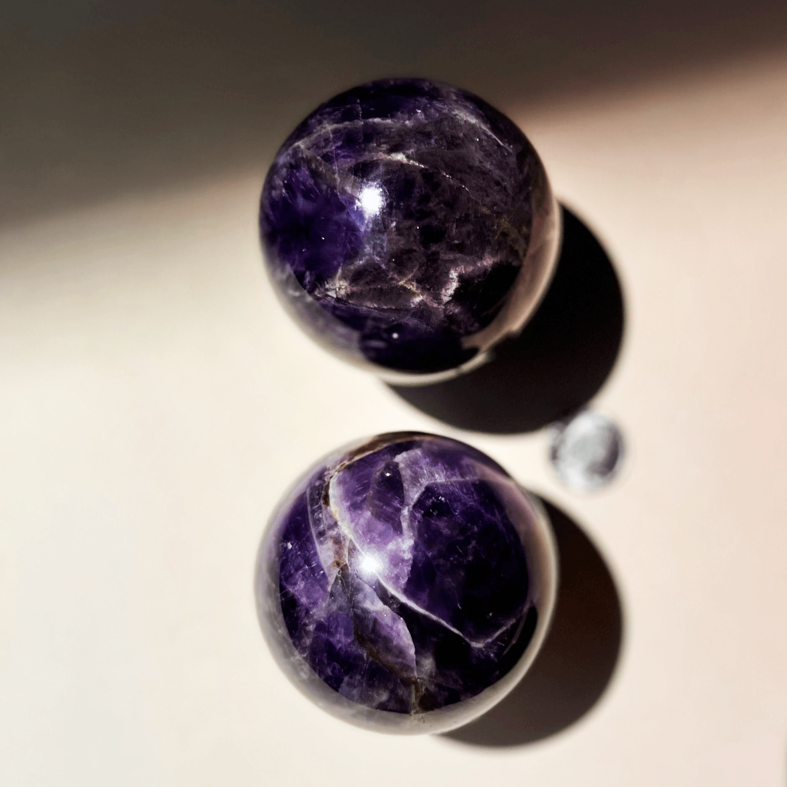 Two purple amaethyst crystal balls on a neutral background