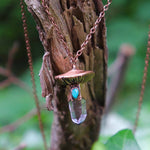 Close-up of mushroom necklace pendant with crystal and turquoise on tree bark