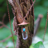 Close-up of mushroom necklace pendant with crystal and turquoise on tree bark