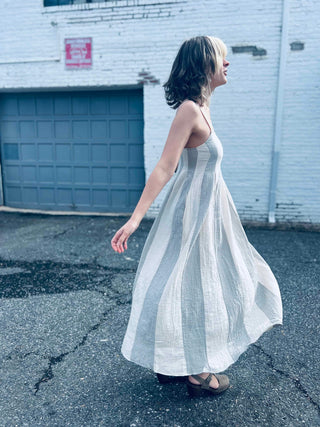 neutral toned striped midi dress styled with a trendy white city background