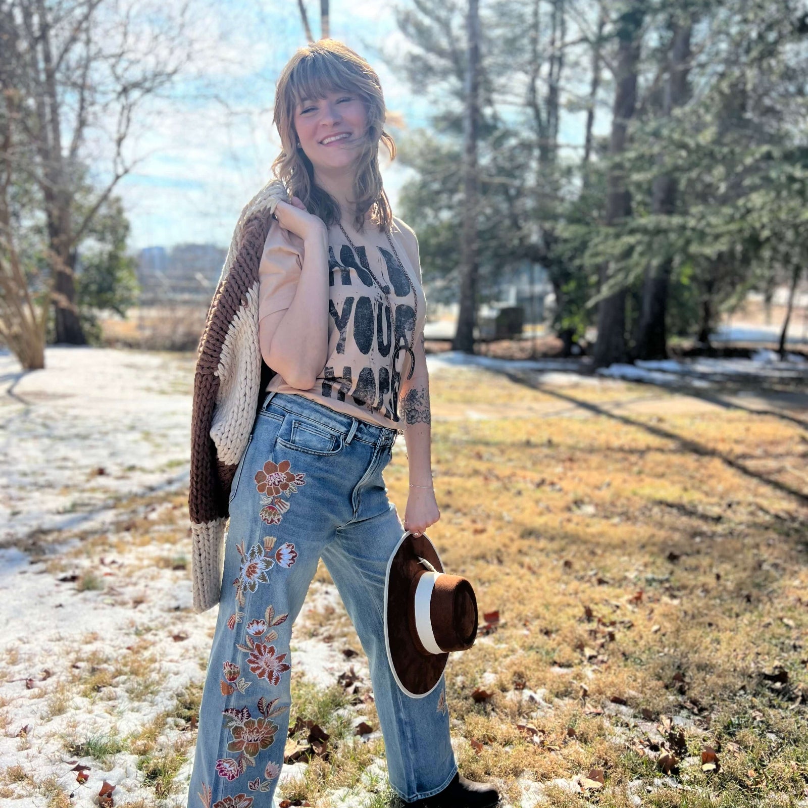 Woman wearing Hold Your Horses graphic t-shirt styled with jeans boho western outfit