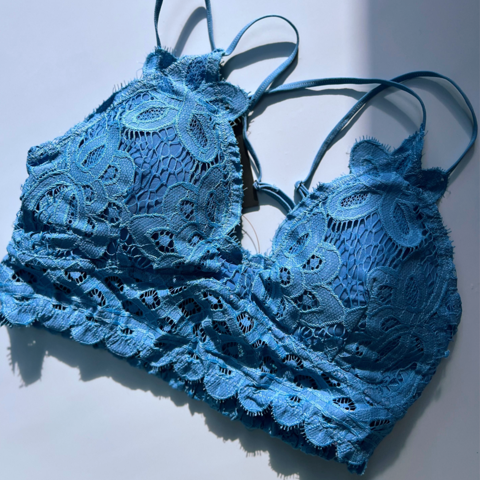 The blue Criss-Cross Back Lace Bralette on a blue background.