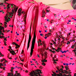 An up-close image of a woman wearing the Embellished Sequin Scallop Crop Top with a black skirt, showing off the back.