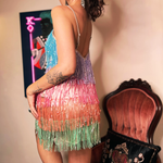 A woman wearing the Mini Disco Dress while holding a disco ball in front of a funky background, showing off the back.