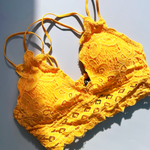 The mustard Criss-Cross Back Lace Bralette on a blue background.