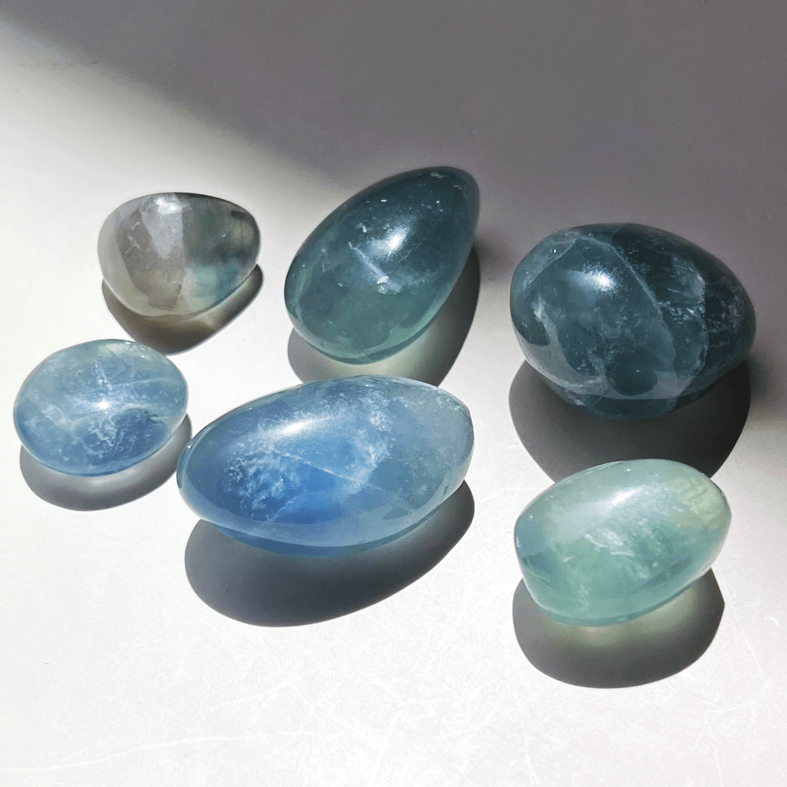 Blue green fluorite tumble stones shown with coin for size reference polished natural crystals