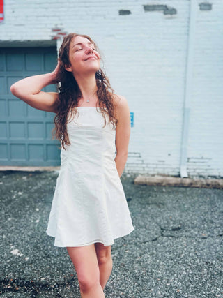 cute summer boho dress in front of white brick backdrop