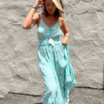 Woman wearing a light blue dress against a textured gray wall.