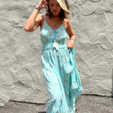 Woman wearing a light blue dress against a textured gray wall.