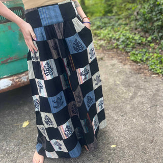 Bohemian patchwork skirt with nature motifs in black and cream tones close up with hand in pocket