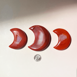 Hand holding carnelian crescent moon crystal showing size reference and polished natural stone detail