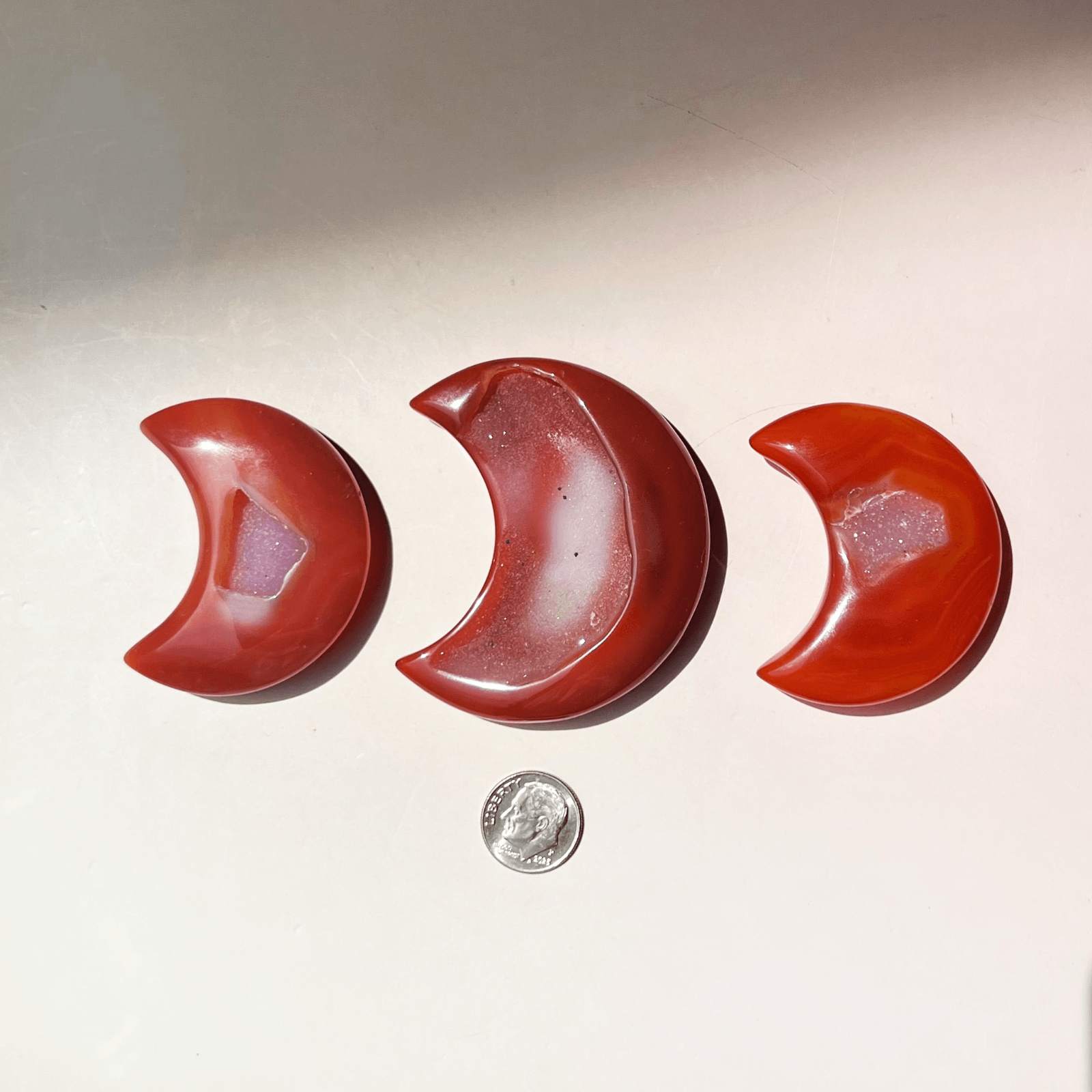 Hand holding carnelian crescent moon crystal showing size reference and polished natural stone detail