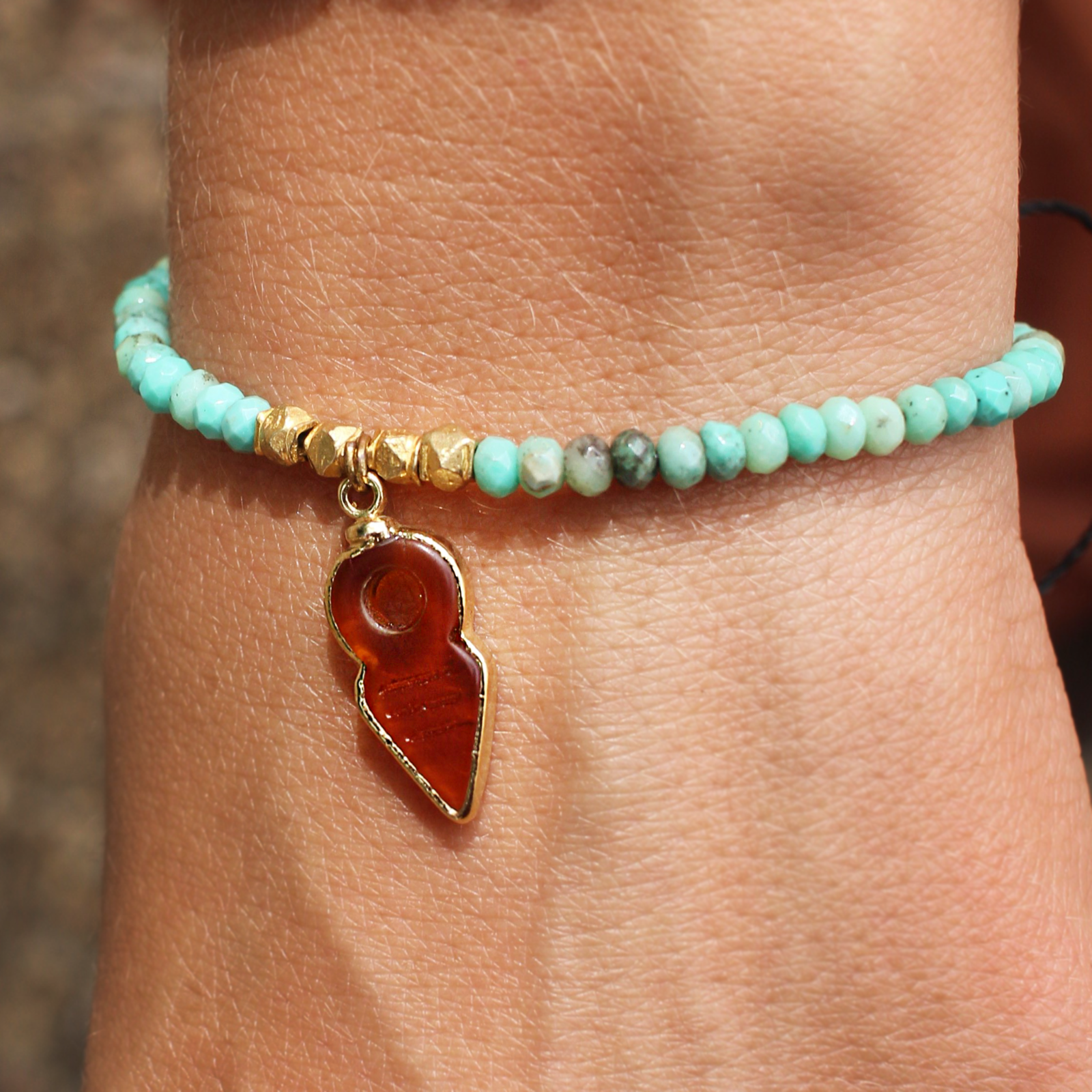 An up close image of someone wearing the 22kt Overlay Faceted Chrysoprase and Carnelian Bracelet.