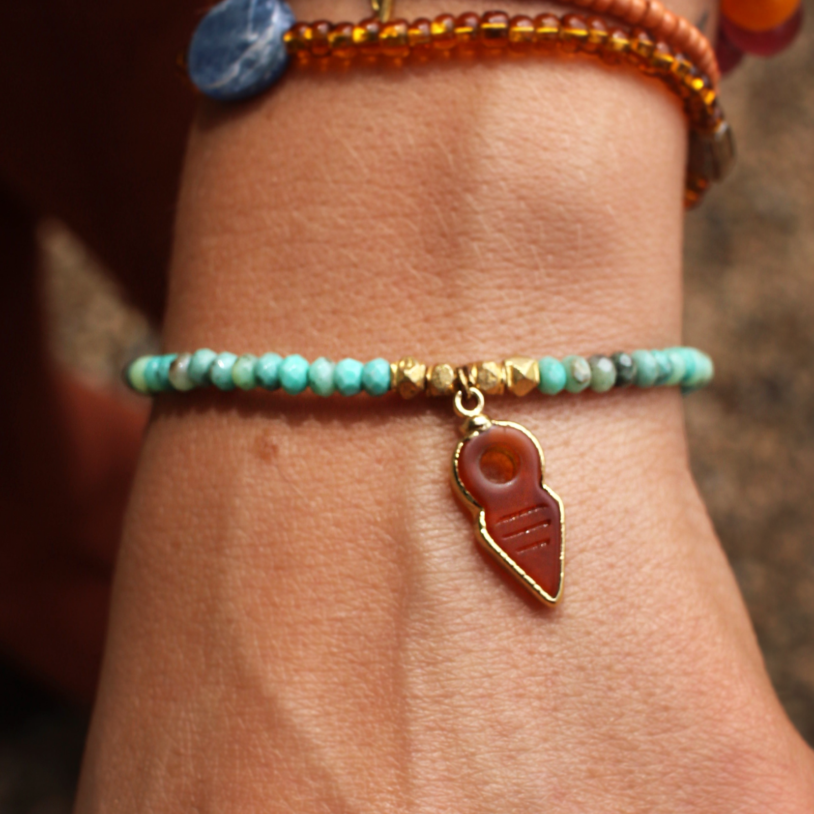 An up close image of someone wearing the 22kt Overlay Faceted Chrysoprase and Carnelian Bracelet.