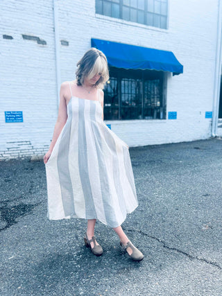 Boho-style striped cotton midi dress with pintuck details outside white brick wall