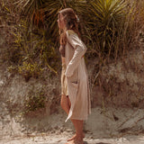 A woman wearing the earthy Sun Ray Cardigan in front of a sand dune at the beach.