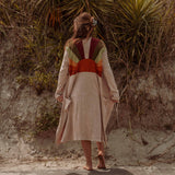 A woman wearing the earthy Sun Ray Cardigan in front of a sand dune at the beach.