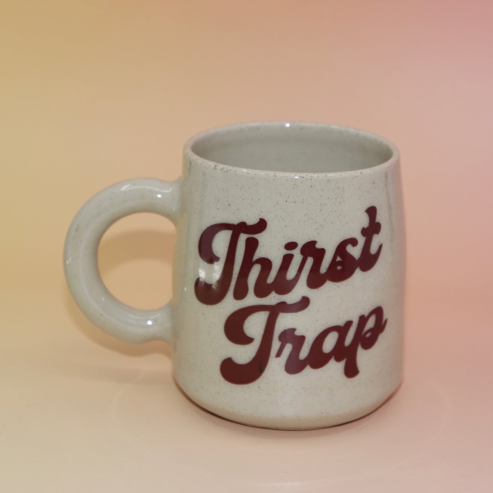 Front view of handmade mug with “Thirst Trap” in retro burgundy script