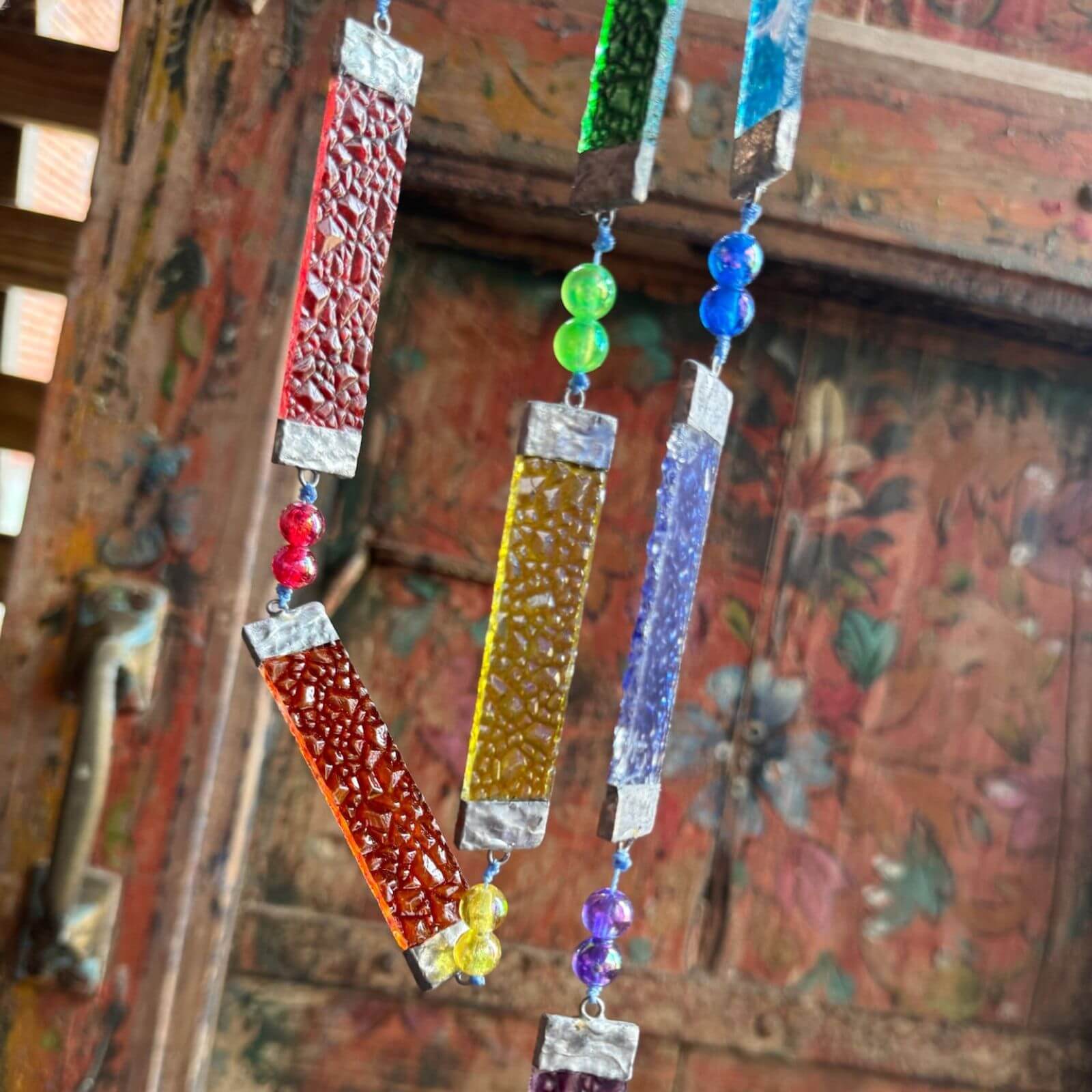 Boho rainbow window sun catcher made with stained glass panels and crystal beads, light-catching home decor accent.
