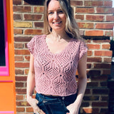 close up of a lightweight crochet knit detailing on a cotton v-neck cap sleeve top standing in front of the boho depot retail store 