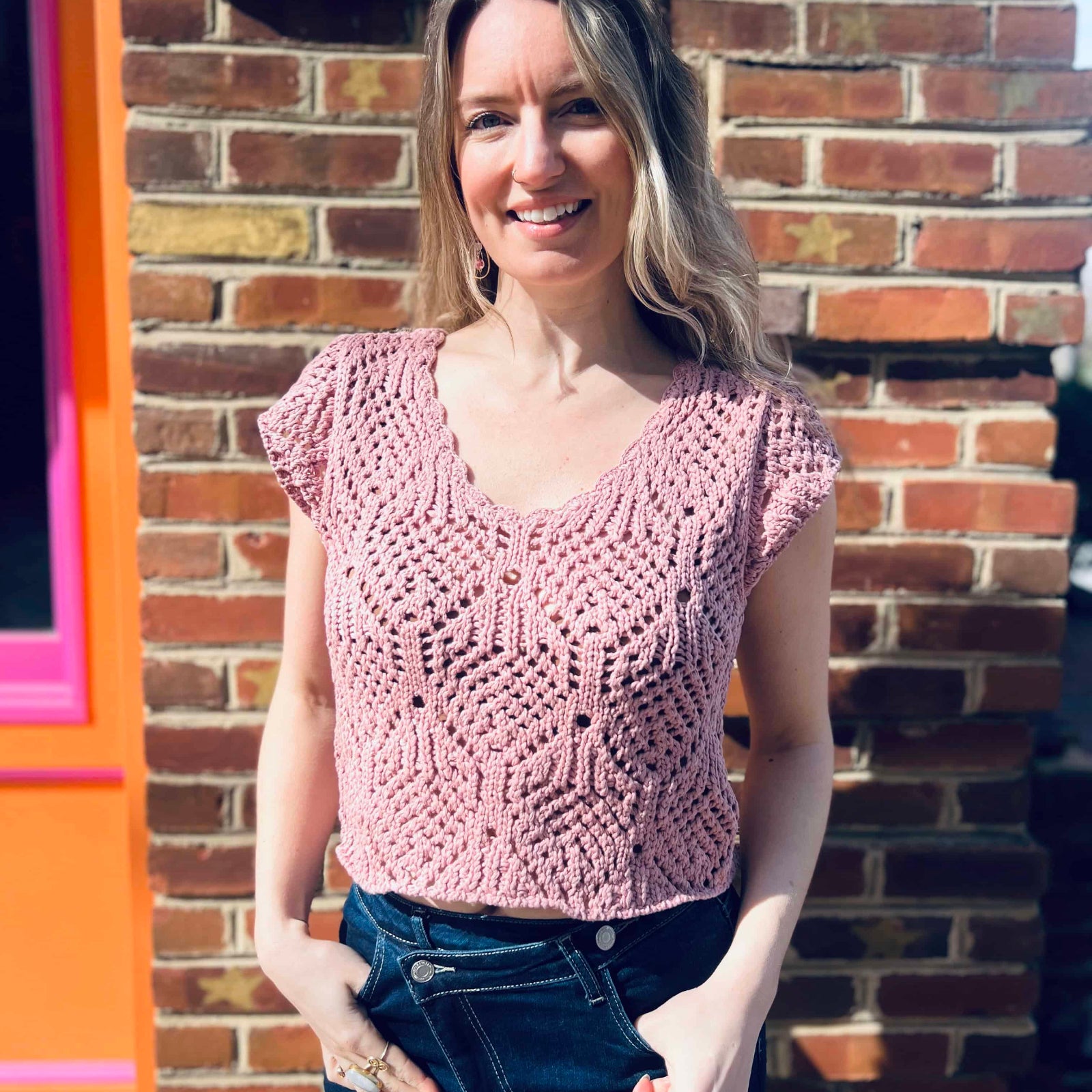 close up of a lightweight crochet knit detailing on a cotton v-neck cap sleeve top standing in front of the boho depot retail store 