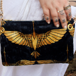 A woman holding the Black and Gold Heron Chain Strap Velvet Crossbody Bag.