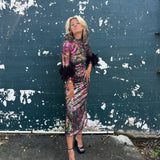 Woman in a colorful disco dress standing against a peeling blue wall.