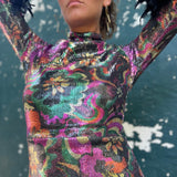 Person wearing a colorful, patterned dress with a dark background