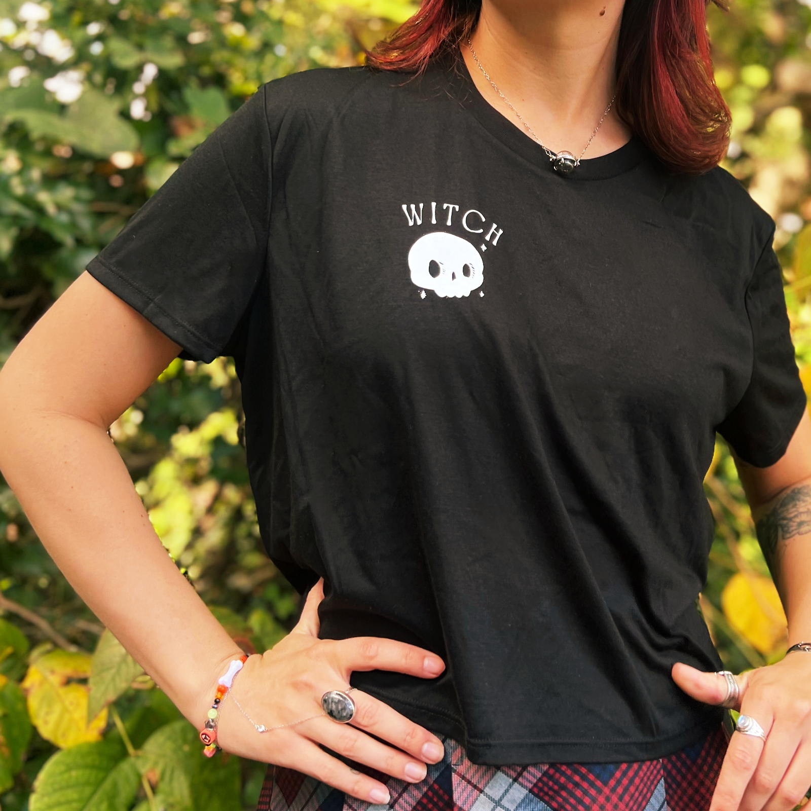 A woman wearing the Do No Harm Take No Sh*t Cropped Top with a red and navy plaid skirt.