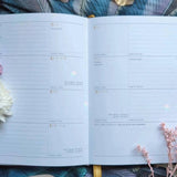 Open planner with floral decorations on a textured surface